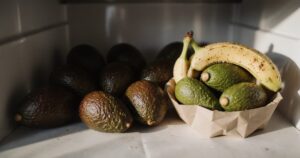 Aufgeschnittene Avocados auf Holzbrett mit Zitronen und Glasbehältern in moderner Küche